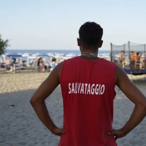 Vista panoramica spiaggia con bagnino di spalle in primo piano