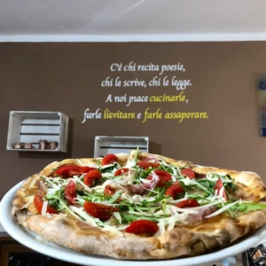 Pizza con frase su muro come sfondo da Pizzeria "Da Rino"